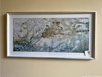 Full view of the framed abstract print hung on a cream wall.