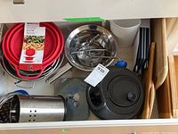 Overview photo of kitchen drawer with assorted kitchen items including cutting boards, strainers, salad spinner, cast iron pot, and other utensils.