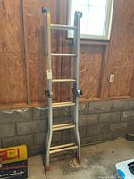 Full view of the Featherlite aluminum ladder showing rungs, black adjustment mechanisms, and red rubber feet.