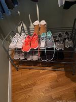 Seven pairs of ladies shoes arranged on metal shoe rack, showing different styles and colors with wear visible on shoes.