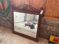 Full front view of large rectangular mirror in wooden frame with wrought iron detail on top, showing general condition and overall appearance.