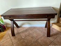 Full view of the wood hall table with fold-out leaves in its closed position showing the slatted top and curved legs.