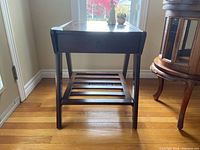 Full view of the front of the dark wood side table showing drawer and slatted lower shelf.