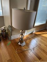 Full view of the table lamp including beige fabric shade and chrome base with glass ball accents.