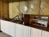 Wide view of hand tools arranged on top of white cabinetry against insulated basement wall.