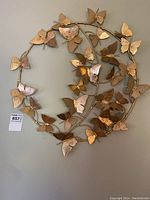 Full view of the round metal wall decor showing the gold 3D butterflies on a circular frame.