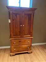Front view of wooden cabinet showing two doors on upper section and two drawers on bottom section.
