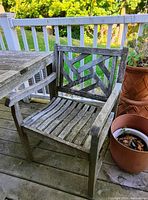 Front-right view of one weathered teak patio chair showing slatted seat and geometric back