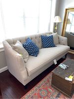 Front three-quarter view of beige tufted sofa with pillows