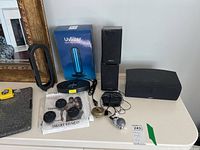 Overview of all items including Uvlizer lamp base, Energy Take speakers, wired earphones, fitness pods, and cords on a table.