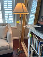 Full view of the metal floor lamp next to a sofa and mirror, showing its height and base structure.