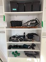 White shelving unit with iron, hair dryer, sewing basket, various small items, sunglasses and weights arranged on shelves