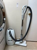 Kenmore Progressive vacuum cleaner assembled with hose and wand, standing upright next to a door.