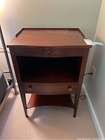 Front view of wooden night stand showing single top drawer, open middle storage, larger bottom drawer, and lower shelf, with scratches on surface.