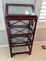 Full view of the wood reading stand showing the adjustable/tilt top and three glass shelves with wooden framing.