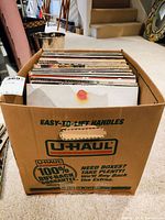 Box filled with vinyl records in cardboard box with U-Haul branding, viewed from above