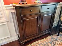 Side view of wooden side cabinet showing the drawer and closed storage doors