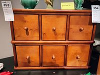 Front view of the wooden storage unit showing six drawers with round knobs and a smooth wood finish.