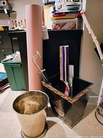 Photo showing two trash bins (green and black), metallic round bin, pink craft paper roll, and items (hand mirror, ruler) in bin.