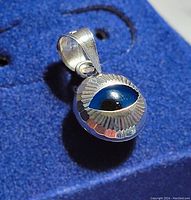 Close-up of white gold evil eye pendant showing dome shape and detailed eye design.