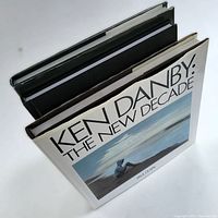 Three hardcover books viewed from an angle, showing Ken Danby's book on top with a dust jacket and two other hardcover books beneath it.