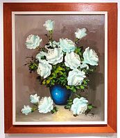 Full frontal image of framed oil painting showing white roses in blue vase on brown background.