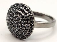 Close up of silver ring's top showing 88 small black diamonds in concentric circle pattern.