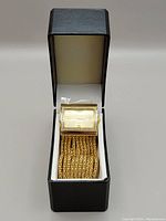 Gold-tone rectangular women's Vivani quartz watch with white crystal bezel in black box with white lining.