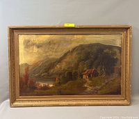 Full front view of the framed primitive landscape oil painting showing the cottage, river, and hills. Frame has chips and wear. Yellow lot number tag visible.