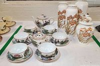 Full view of porcelain teaware set with teapot, sugar bowl, cups, saucers, and three floral vases with matching ginger jar