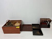 Wide view of the lot showing the wooden storage box on the left, baskets inside, three lacquered trays in the middle, and Japanese wooden lunch caddy on the right.