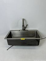 Front view of the stainless steel drop-in sink with faucet mounted, showing rectangular basin and faucet shape.
