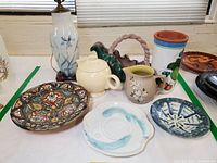 Overview photo of ceramic lamp, Fiesta teapot, pottery bowls and pitchers, terracotta wine cylinder, assorted decorative plates.