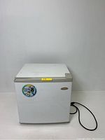 Front view of white Haier compact refrigerator showing door, sticker, and power cord