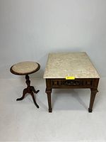 Two mid-century style end tables with marble tops placed against a white wall.