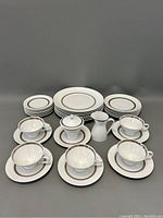 Full set arranged showing cups on saucers, plates behind, and creamer and sugar bowl in front center.