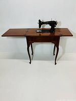 Vintage Graybar sewing machine in a wooden cabinet desk table with folding side panels, shown open.
