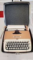 Full view of the beige and cream Smith Corona manual typewriter inside a hard carrying case with lid open.