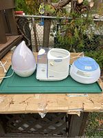 Lot of three humidifiers on outdoor surface, showing all items together