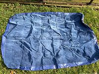 Deflated twin size blue air mattress laid flat on grass, showing overall condition and color.