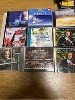 CD jewel cases arranged showing classical, hymn, and vocal music including Andre Rieu, Mario Lanza, Handel Messiah, Daniel O'Donnell, and others.
