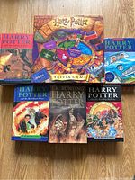 Photo showing 5 Harry Potter novels and one Harry Potter trivia game board laid out on a wooden surface. The book covers feature colorful illustrations and the trivia game board is vibrant with Harry Potter iconography.