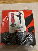 Photo of the inflatable punching bag inside a clear sealed plastic bag showing product branding and usage illustration.