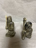 Front view of two inuit hunter figurines placed side by side on fabric background.