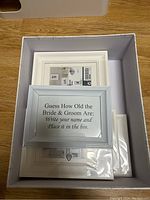 Photo of a card inside white frame with instructions for guessing the age of the bride and groom, packaged with other cards.