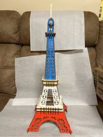 Eiffel Tower model painted in red, white, and blue colors, standing on a neutral background.