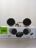 Pair of chrome 3-inch full-range marine speakers placed on top of product box, showing front view with speaker grills and chrome rims.