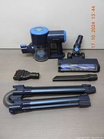 Photo of all vacuum parts laid out: main vacuum unit, motorized brush head, small brush, crevice tool, extension hose, and two bendable wand tubes.