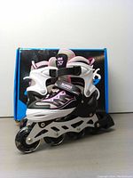 Front view of the 2PM Sports Cytia pink and black inline roller skates with adjustable straps and light-up wheels, placed in front of the product box.