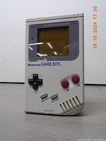 Front view of the Nintendo Game Boy showing the screen, buttons, and speaker grille.